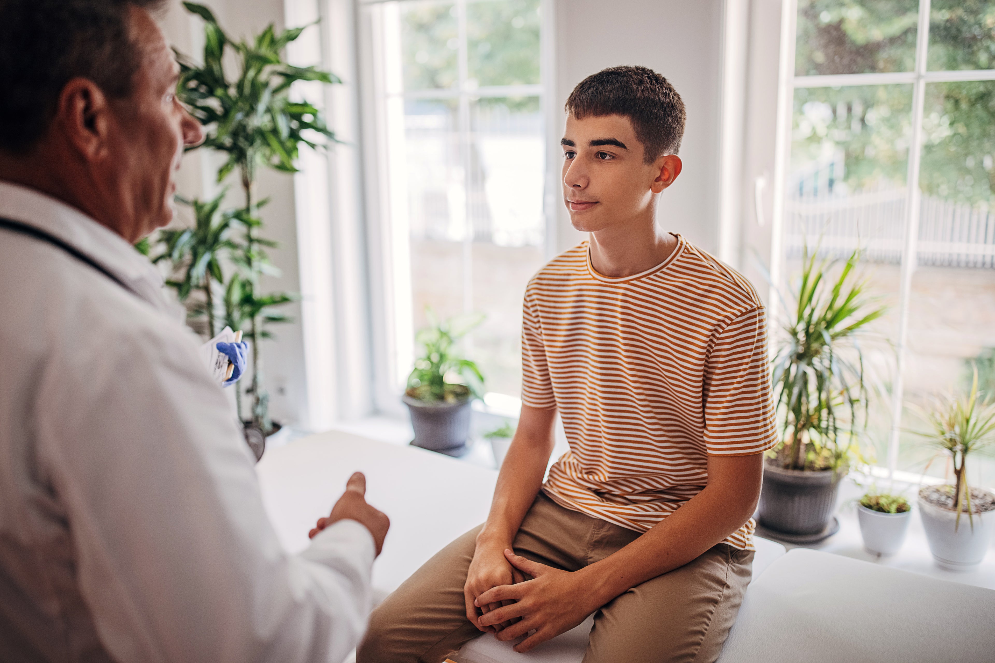 Teenager sitting on doctors bed