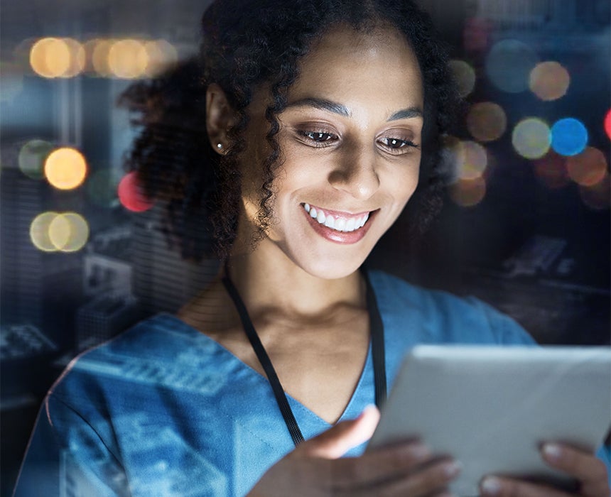 Photo of female doctor, smiling while holding and looking at a tablet screen