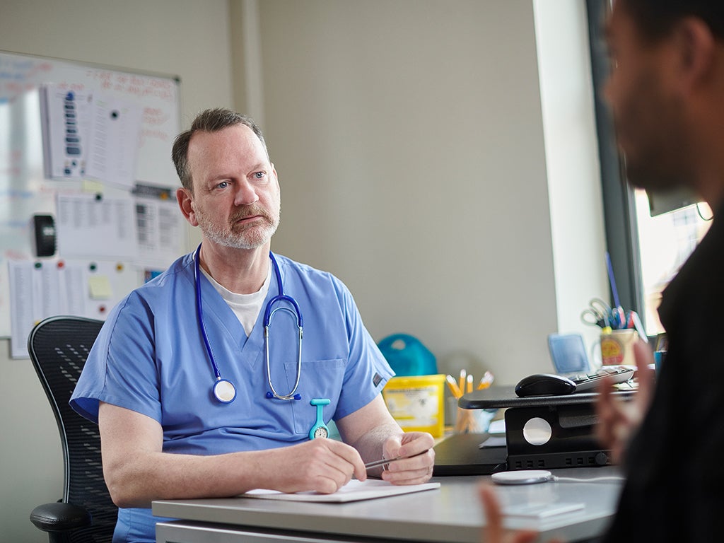 Doctor in scrubs with stethoscope around his neck in consulting room