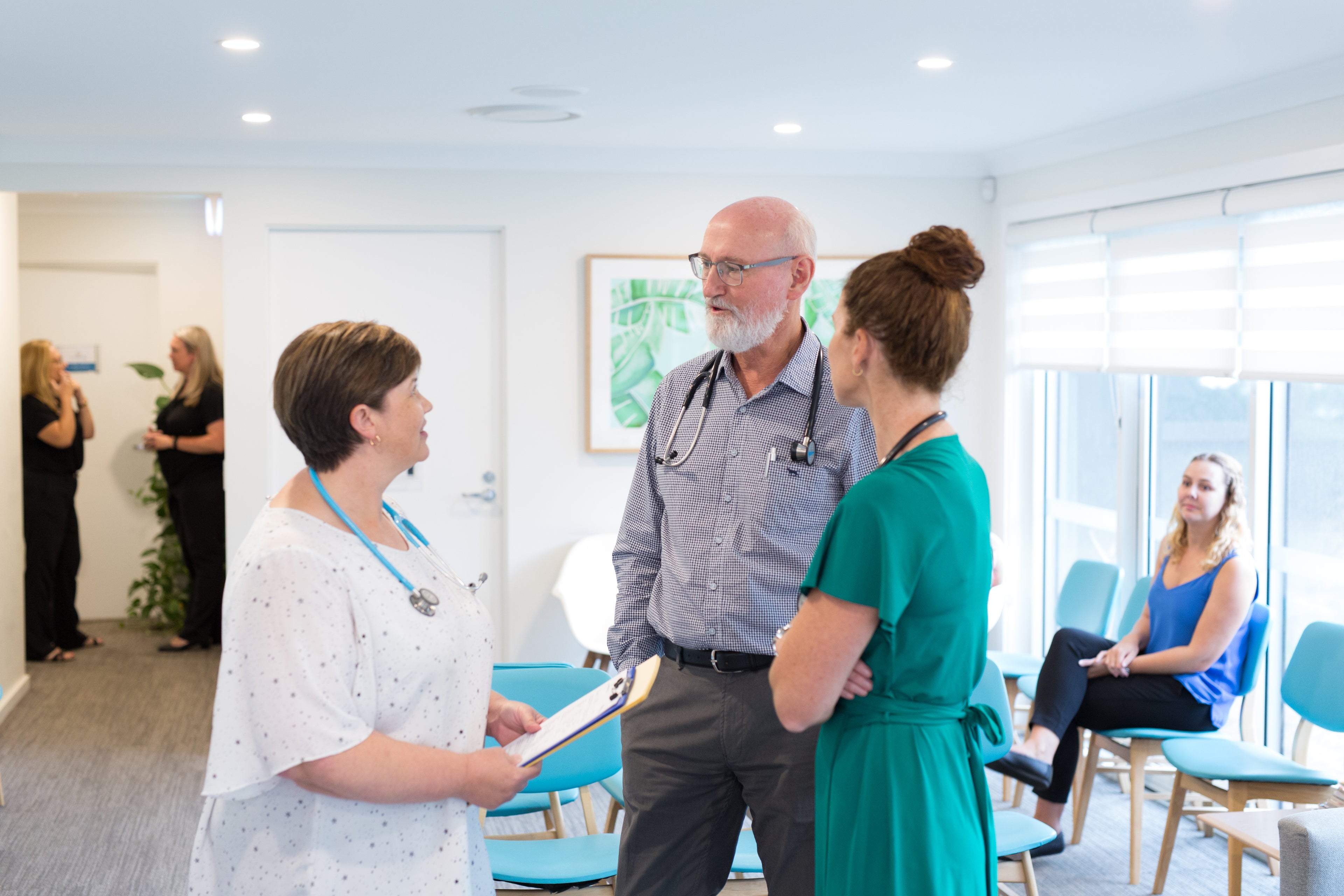 Three doctors talking in a medical practice reception.