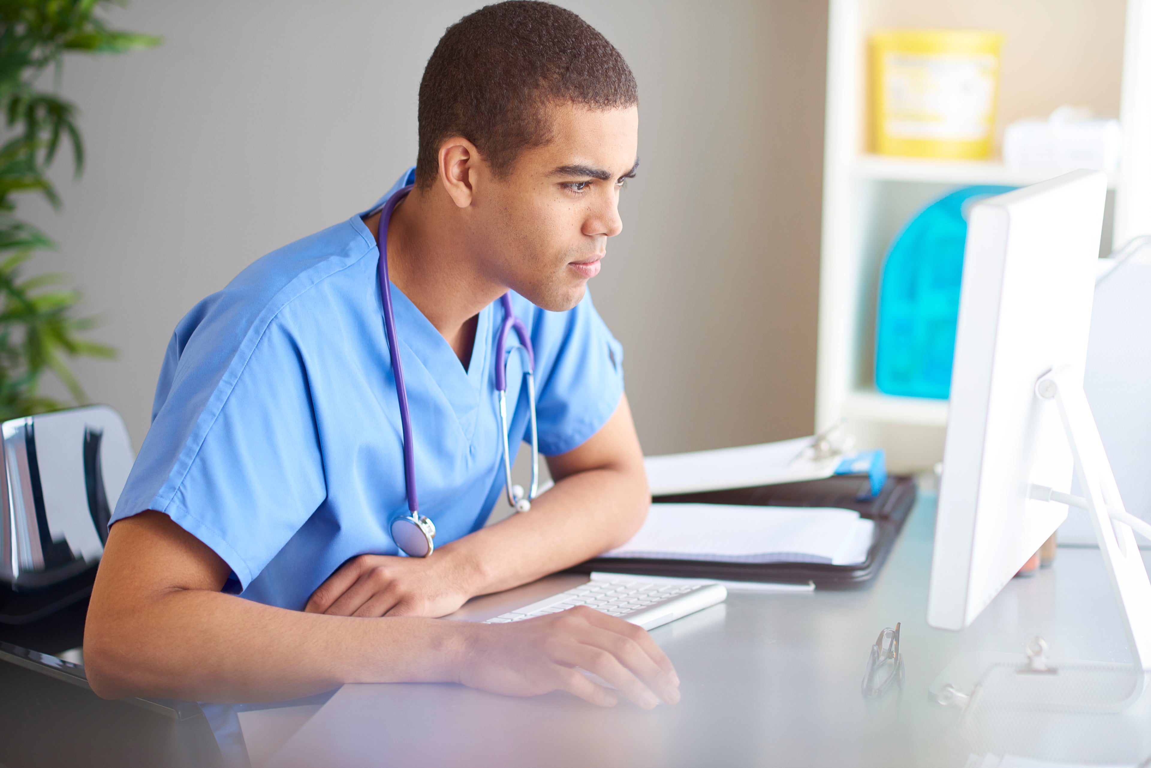 young doctor in scrubs looking at computer