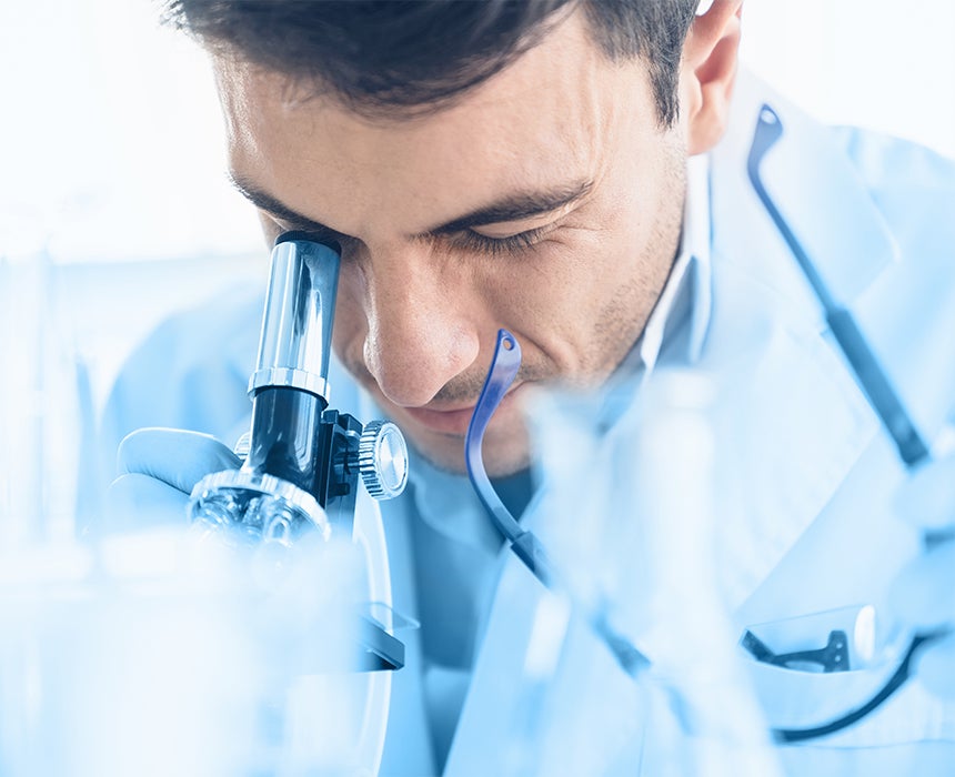 Photo of male researcher looking into microscope