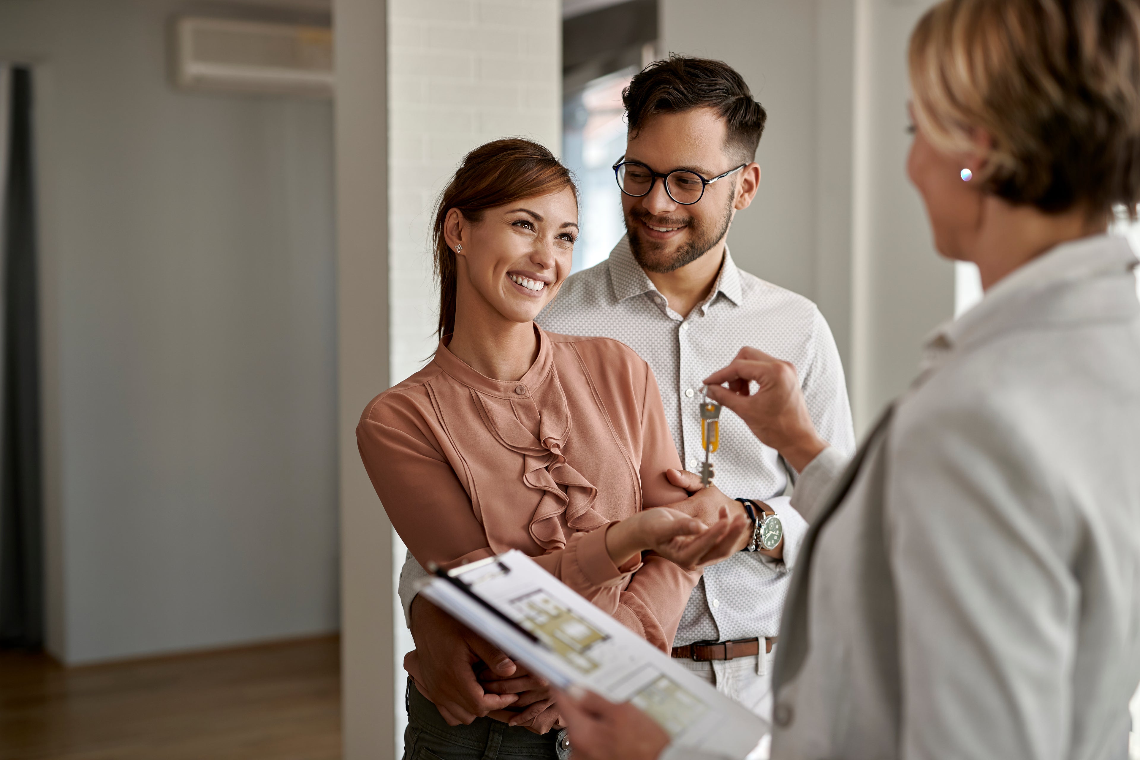 Image of couple receiving keys from a real estate agent for their new home.