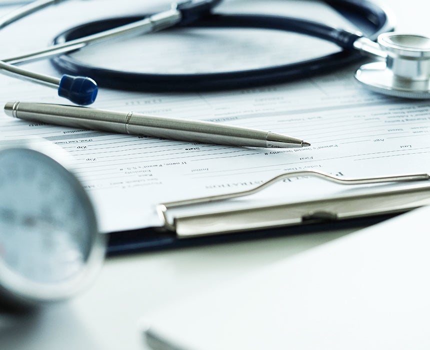 Stethoscope on top of paper clip board with pen