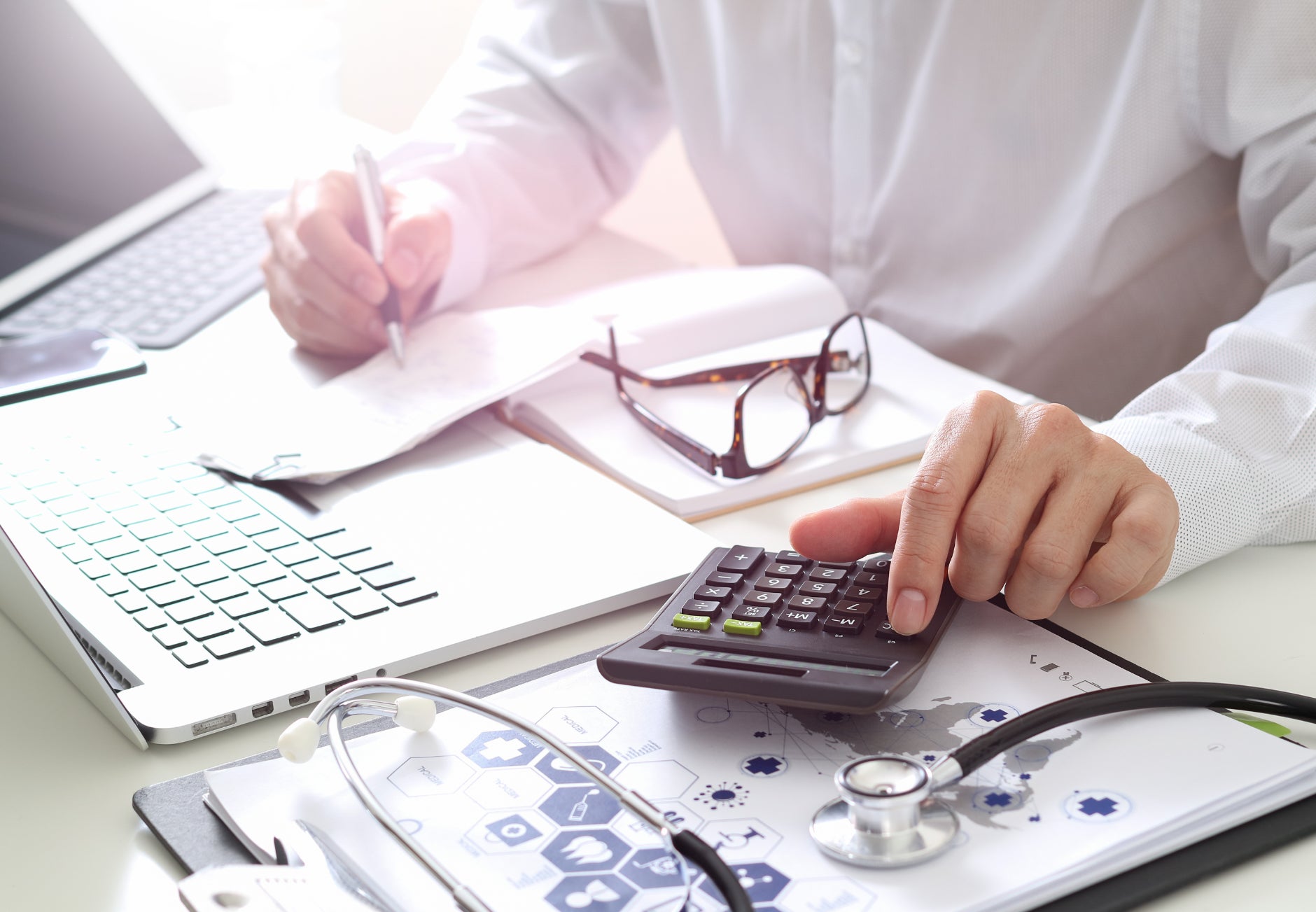 Doctor sitting at desk with calculator 