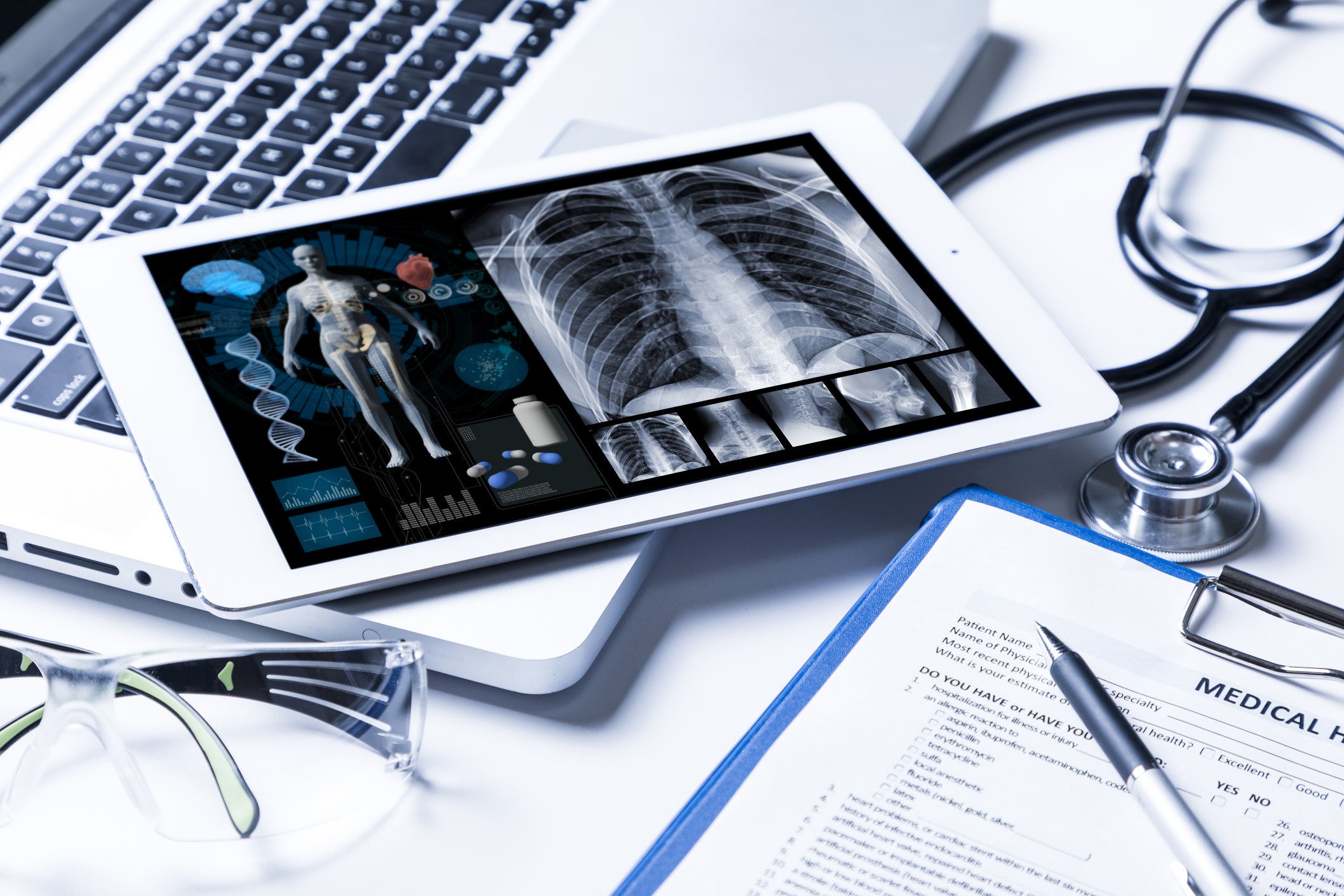 Tablet computer with patient X-ray results sitting on desk with stethoscope