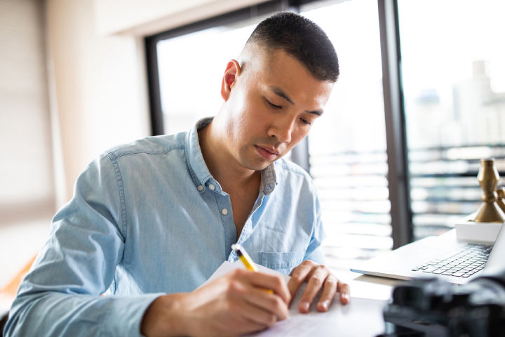 man writing on paper